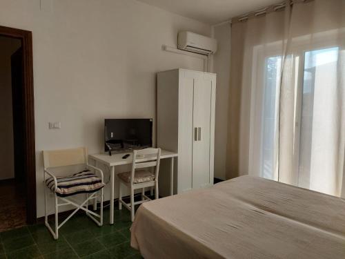 a bedroom with a bed and a desk with a computer at Casa del Sole Guest House in Alghero