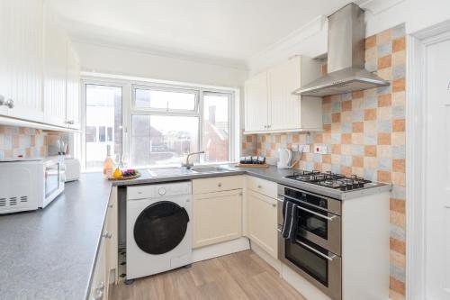 a white kitchen with a sink and a stove at Open Mind Property - Four Bedroom House in Portsmouth