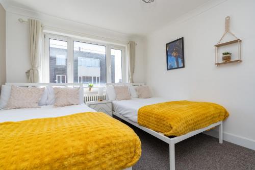 a bedroom with two beds and a yellow blanket at Open Mind Property - Four Bedroom House in Portsmouth