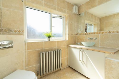 a bathroom with a toilet and a sink and a window at Open Mind Property - Four Bedroom House in Portsmouth