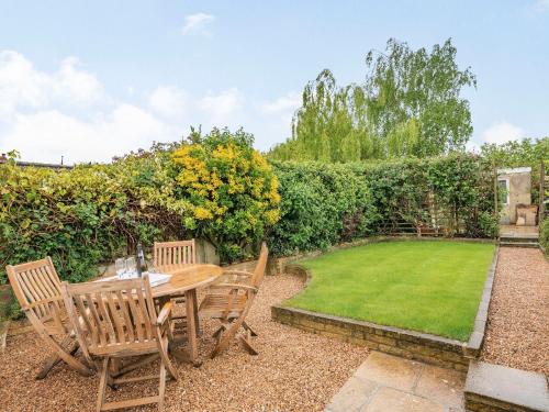 a garden with a wooden table and chairs and a lawn at Stonegarth in Snitterby