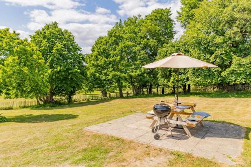 a grill and a table with an umbrella at Secluded 3 bed cottage in private parkland in Brockenhurst