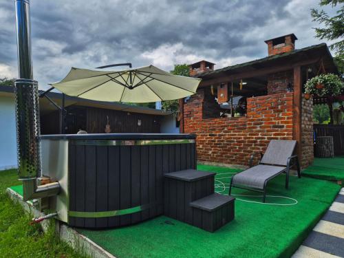 a patio with an umbrella and a chair and a bench at La Nelutu Ceterasu in Ocna Şugatag