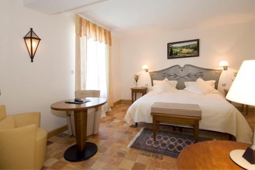 a bedroom with a bed and a table and a chair at Hotel De France in Mende