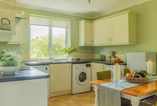 a kitchen with white cabinets and a sink and a dishwasher at Secluded 3 bed cottage in private parkland in Brockenhurst