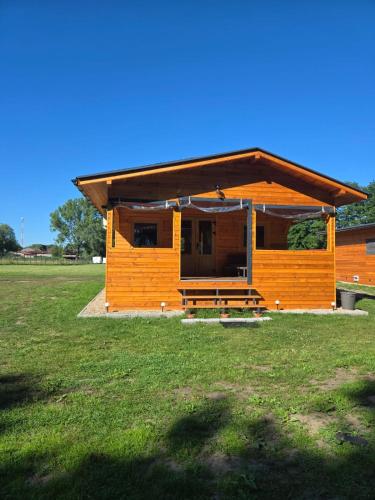 a small wooden house with a bench in a field at Domki Pod Olchowym Dachem Lubie in Gudowo