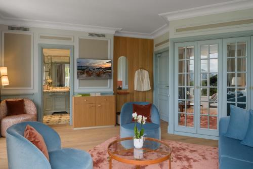 a living room with two blue chairs and a table at Althoff Hotel Villa Belrose in Saint-Tropez