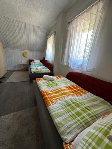 een kamer met twee bedden en een bank en ramen bij Berzsenyi Ház in Balatonfenyves