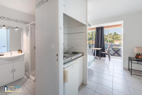 Il comprend une cuisine blanche avec un évier et une salle de bains. dans l'établissement Camping Oléron St-Tro'Park, à Saint-Trojan-les-Bains