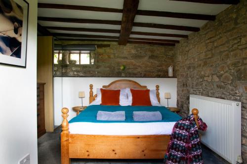 a bedroom with a wooden bed in a stone wall at Cleave Cottage in Crackington Haven