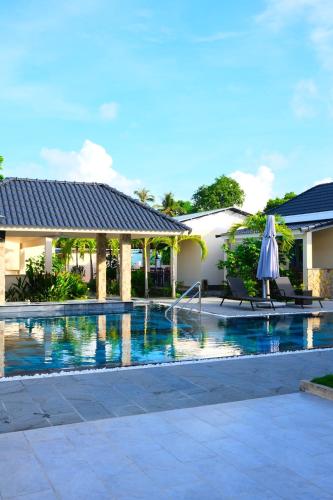 a swimming pool with an umbrella next to a house at LAM BUNGALOW Resort & Spa in Phu Quoc