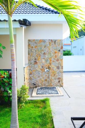 a stone shower in the side of a house with a palm tree at LAM BUNGALOW Resort & Spa in Phu Quoc