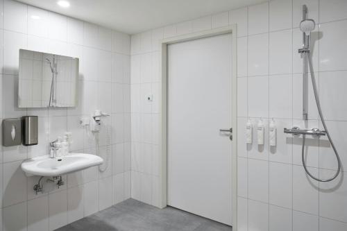 a white bathroom with a shower and a sink at Four Points Flex by Sheraton Essen in Essen