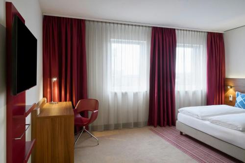a hotel room with a bed and red curtains at Four Points Flex by Sheraton Essen in Essen