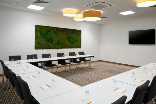 a conference room with white tables and chairs and a flat screen tv at Four Points Flex by Sheraton Essen in Essen