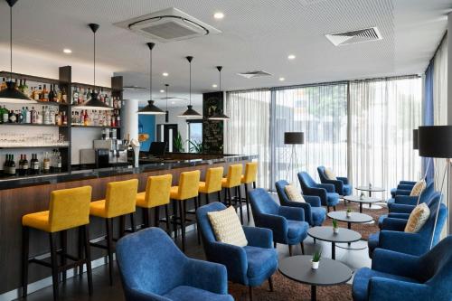 a bar in a hotel with blue and yellow chairs at Four Points Flex by Sheraton Essen in Essen
