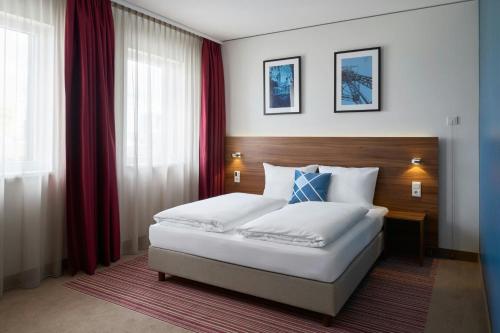 a bedroom with a large white bed with red curtains at Four Points Flex by Sheraton Essen in Essen