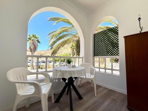 Un comedor con mesa y sillas y una ventana. en amazing apt Playa del Cura, en Mogán