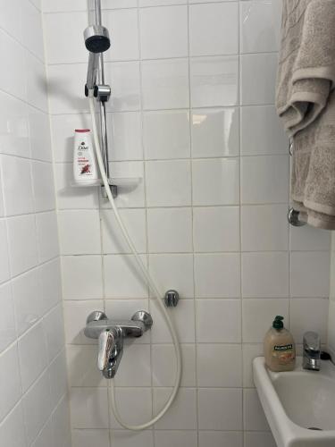 a shower with a hose in a white tiled bathroom at Lauttasaari Studio in Helsinki