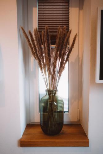 a green vase sitting on a window sill with flowers at Sedmé Nebe Apartmán in Děčín