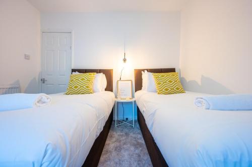 two twin beds in a room with white walls at Silver Street by Tŷ SA in Troed-y-rhiw
