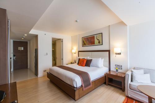 バンコクにあるOakwood Residence Sukhumvit 24 Bangkokのベッドとソファのあるホテルの部屋