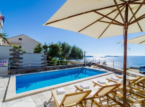 una piscina con sillas y sombrilla en Apartments Villa Capitano, en Mlini