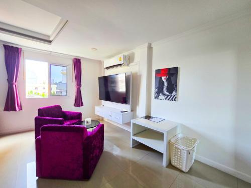 a living room with a purple chair and a tv at Titanic Residence-7 minute walk to the Beach in Pattaya Central