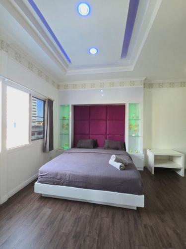 a bedroom with a large bed with a purple headboard at Titanic Residence-7 minute walk to the Beach in Pattaya Central