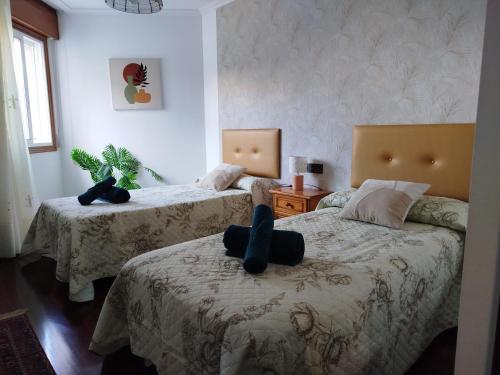 Un dormitorio con dos camas con una persona sentada en la cama. en Apartamento Xaquina, en Melide