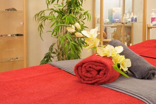 a red towel with flowers on top of a bed at Hotel Tyrol - Oberstaufen PLUS Partner in Oberstaufen