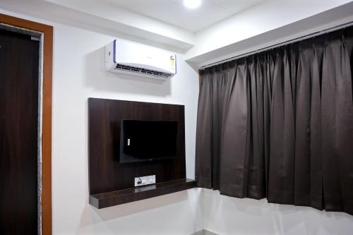 a room with a tv and a black curtain at Hotel Brook View in Surat