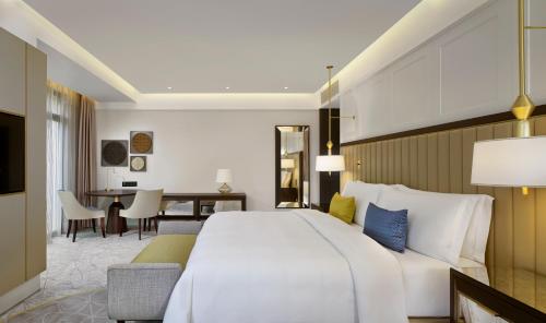una camera da letto con un grande letto bianco e una scrivania di The Alexander, a Luxury Collection Hotel, Yerevan a Yerevan