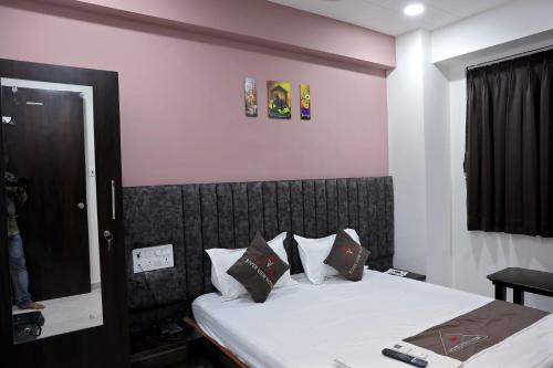 a bedroom with a bed with white sheets and a mirror at Hotel Brook View in Surat