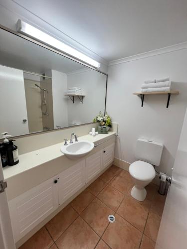 a bathroom with a sink and a toilet and a mirror at Salty waves - D246 in Port Douglas