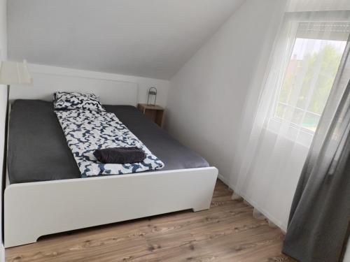 a small bedroom with a bed and a window at Dömper Döme Apartman in Balatonlelle
