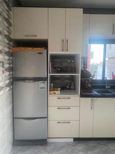 a kitchen with a refrigerator and white cabinets at Appartement complet meublé 2 chambres in Tamraght Ouzdar