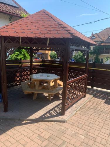 a wooden gazebo with a picnic table in it at Căsuța cu Izvor in Călimăneşti