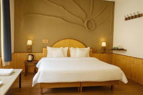 a bedroom with a large bed with white sheets at Beholden Stay and Cafe - A Luxury Boutique Hotel in Manali in Manāli