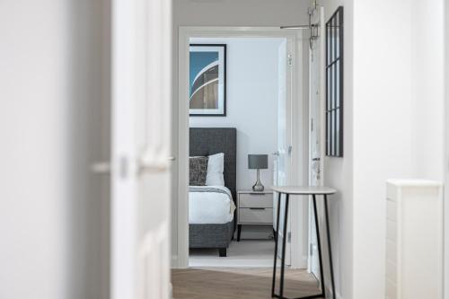 a bedroom with a bed and a table and a mirror at Birchgrove Christchurch Apartments Exclusively for 65s in Leatherhead
