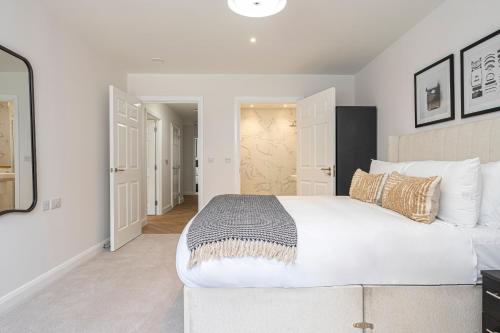 a bedroom with a large white bed and a mirror at Birchgrove Christchurch Apartments Exclusively for 65s in Leatherhead