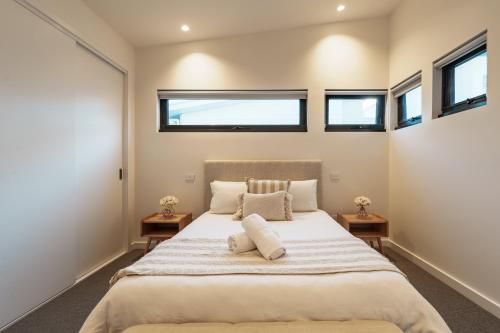 a bedroom with a large bed with two windows at Hamilton By the Bay 3 Newly Built in Safety Beach