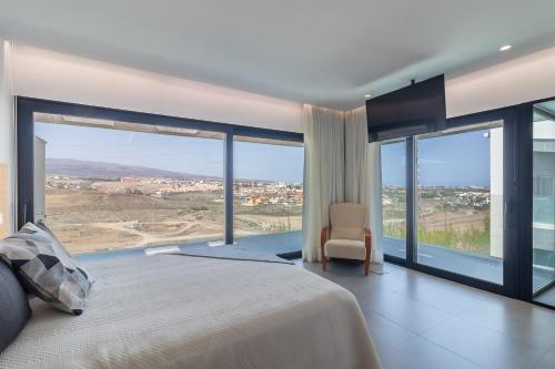 a bedroom with a large bed and large glass windows at Villa Gold Star Meloneras in Meloneras
