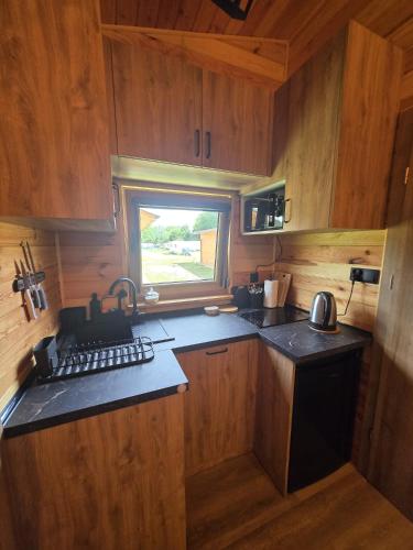 a small kitchen with wooden cabinets and a window at Domki Pod Olchowym Dachem Lubie in Gudowo