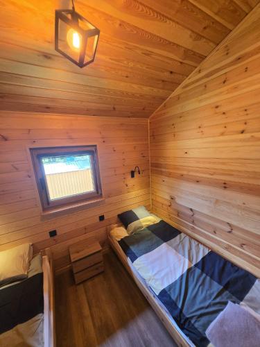 a room with two beds in a wooden cabin at Domki Pod Olchowym Dachem Lubie in Gudowo