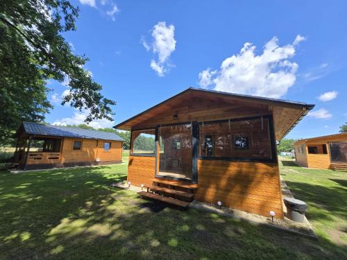 a small cabin in a field with a grass yard at Domki Pod Olchowym Dachem Lubie in Gudowo