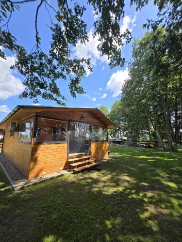 a small cabin in a grassy field with trees at Domki Pod Olchowym Dachem Lubie in Gudowo