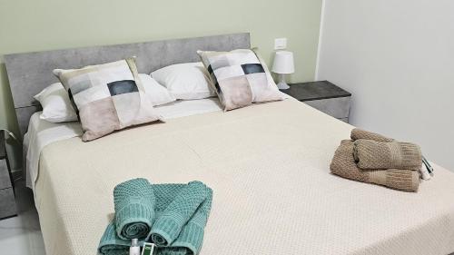 Elle comprend un grand lit blanc avec des oreillers et des serviettes. dans l'établissement Appartamenti Ohana, à Reggio de Calabre