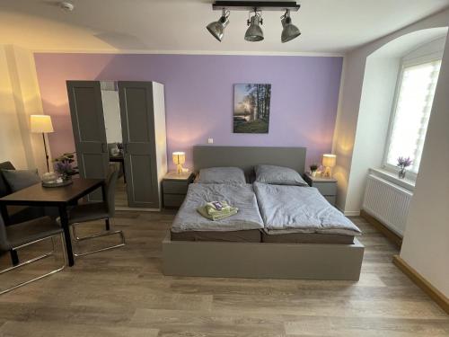 a bedroom with purple walls and a bed and a table at Haus Delphinen in Lübben