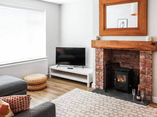 a living room with a fireplace and a television at Cae Garw - Uk47587 in Caernarfon